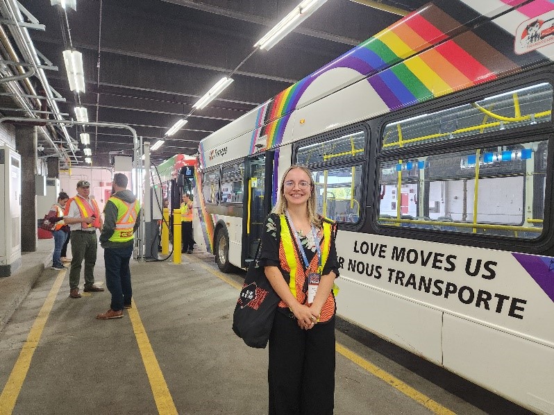 A person standing in front of a busDescription automatically generated